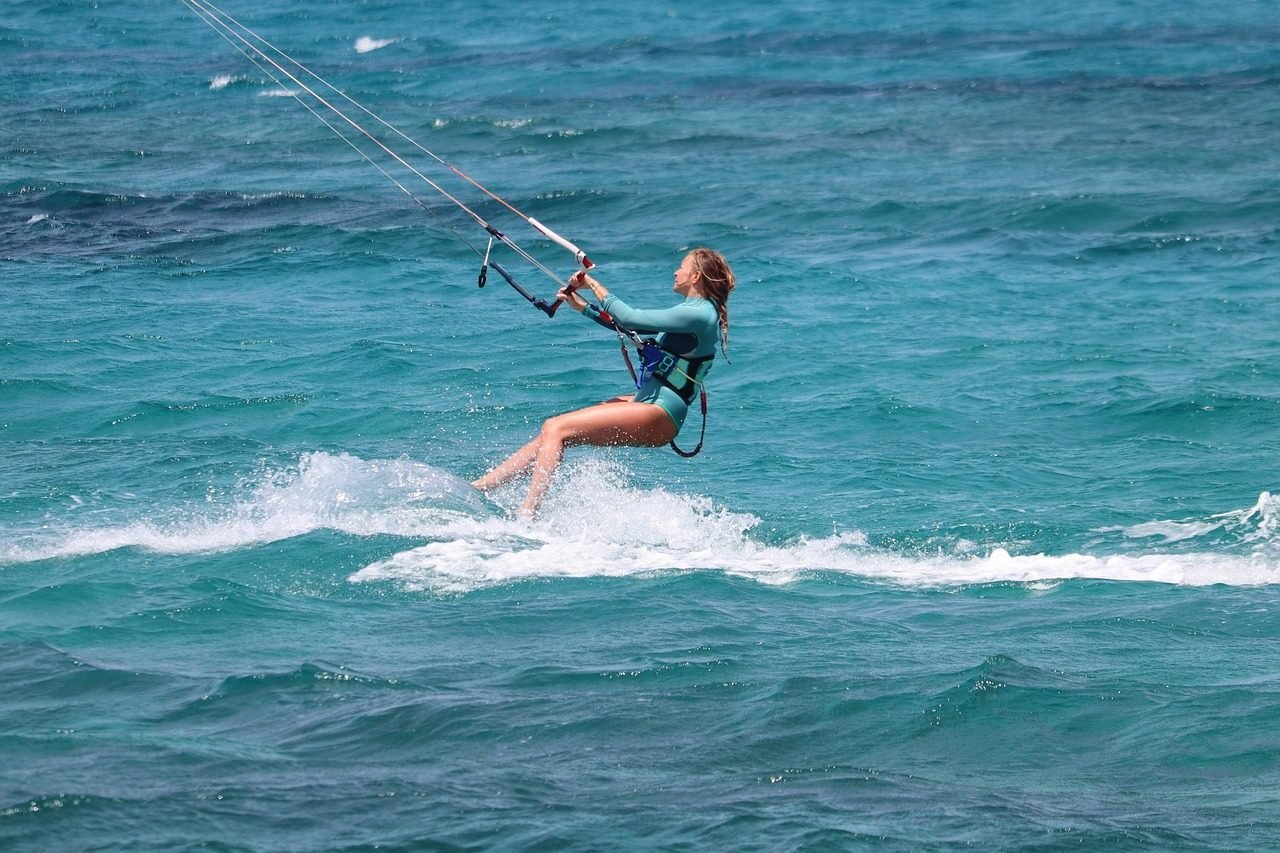 Kitesurfer riding across blue water near a Zanzibar beach
